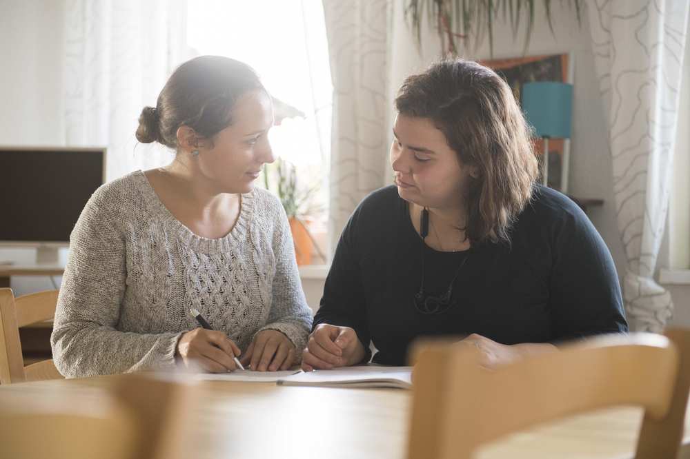 Zwei junge Frauen sitzen am Tisch und schreiben.