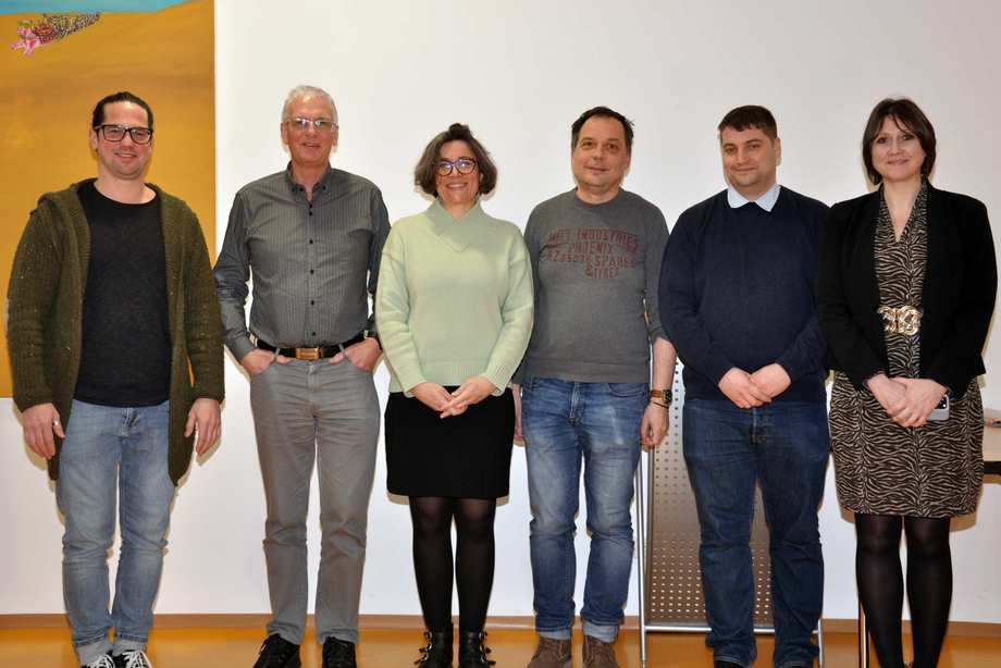 Das Gruppenfoto zeigt vier Männer und zwei Frauen, die nebeneinander stehen und lächeln.