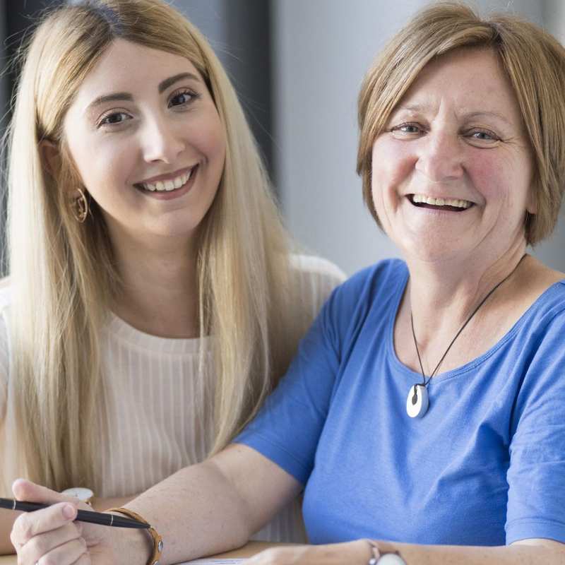 Zwei Frauen sitzen lachend nebeneinander.