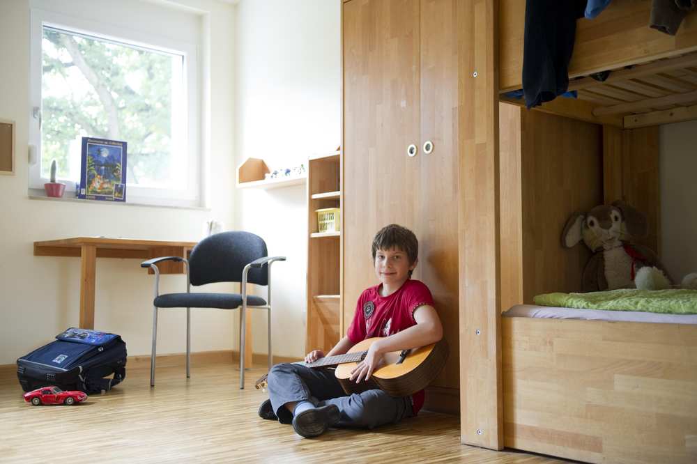 Ein Junge sitzt auf dem Boden und spielt Gitarre.