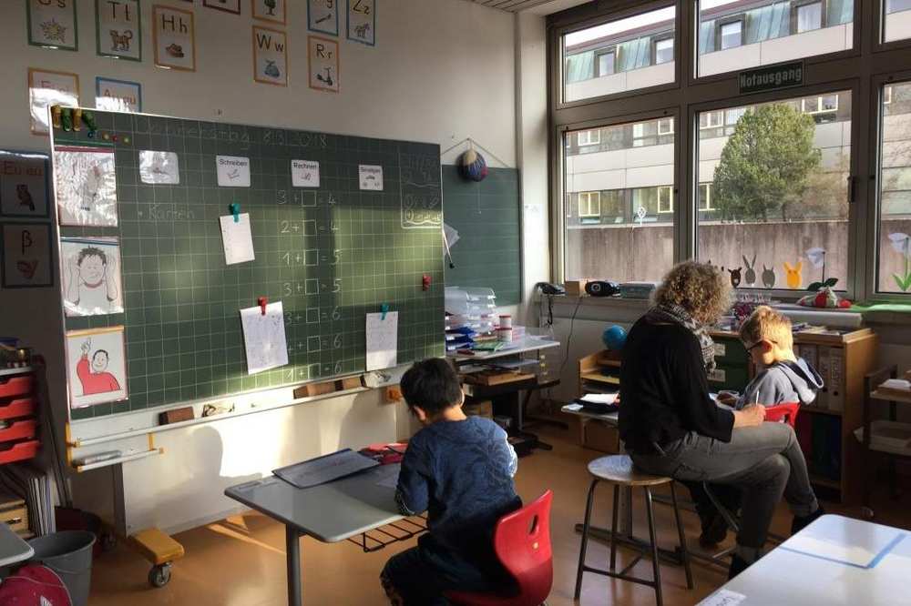 Eine Lehrerin lernt mit zwei Kindern im Klassenzimmer.