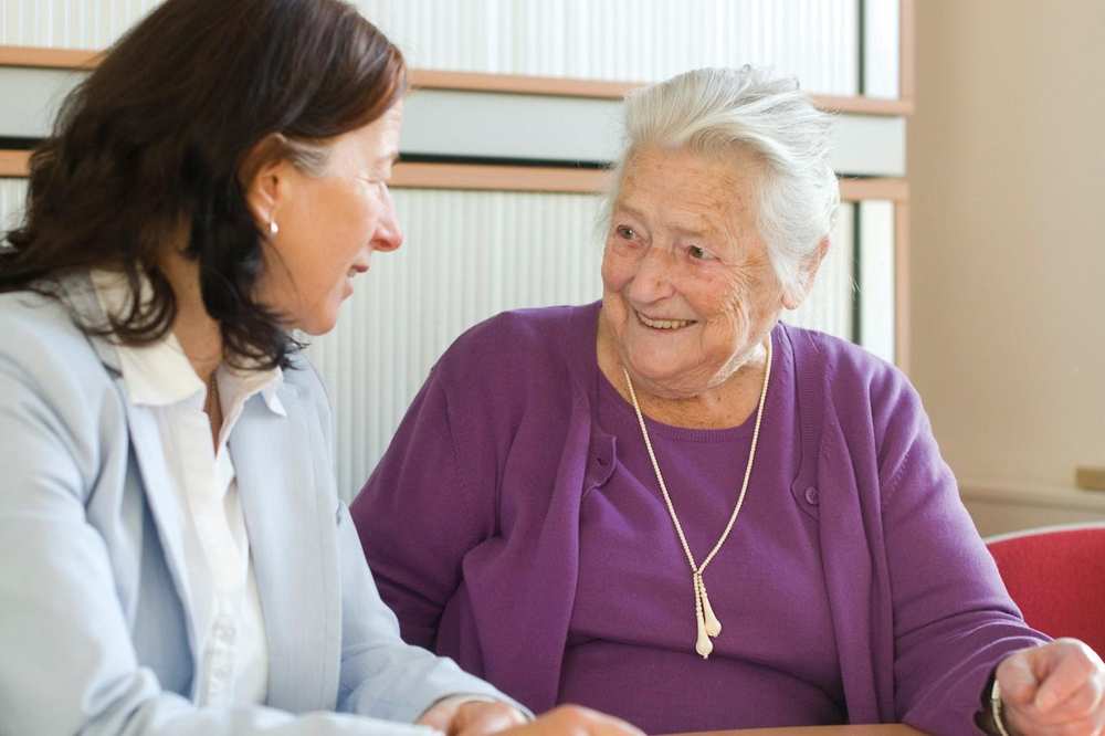 Eine Seniorin im lila Pullover im Gespräch mit einer Mitarbeiterin der Seniorenzentrums am Tiergärtner Tor.