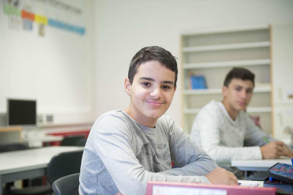 Zwei Schüler sitzen im Klassenzimmer an ihren Schulbänken.