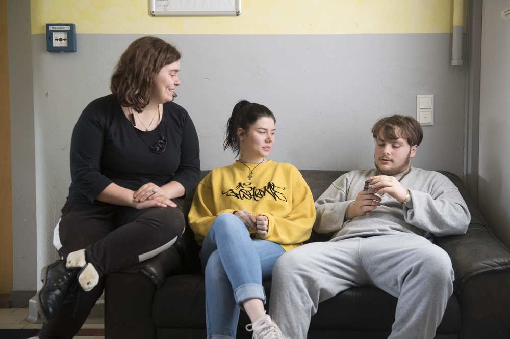 Drei Jugendliche sitzen entspannt auf der Couch.