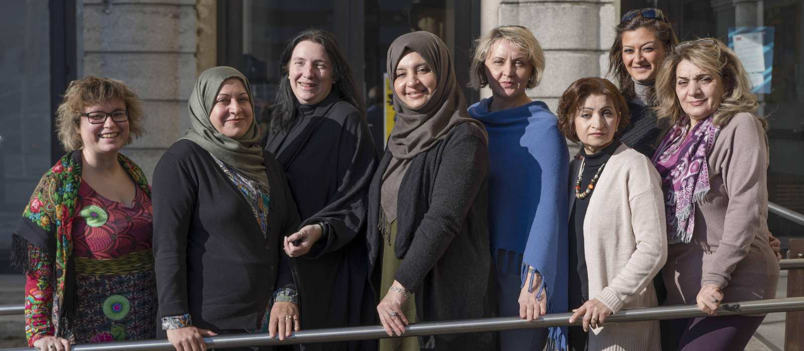 Einbe Gruppe Frauen unterschiedlicher Herkunft stehen vor einem Haus.