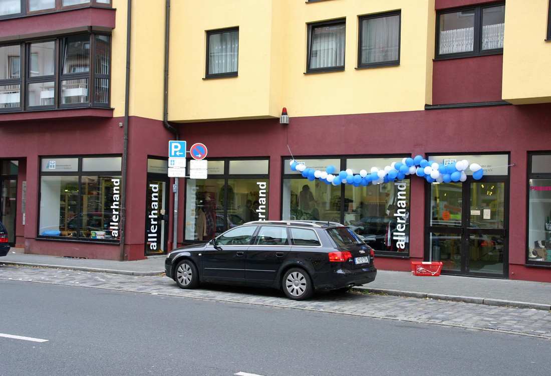 Außenansicht des allerhand-Geschäfts in der Rothenburger Straße. Die Fenster sind mit blauen und weißen Ballons geschmückt. Davor steht ein schwarzes Auto.