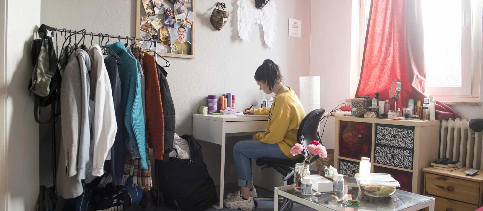 Ein Mädchen sitzt in ihrem Zimmer am Schreibtisch.