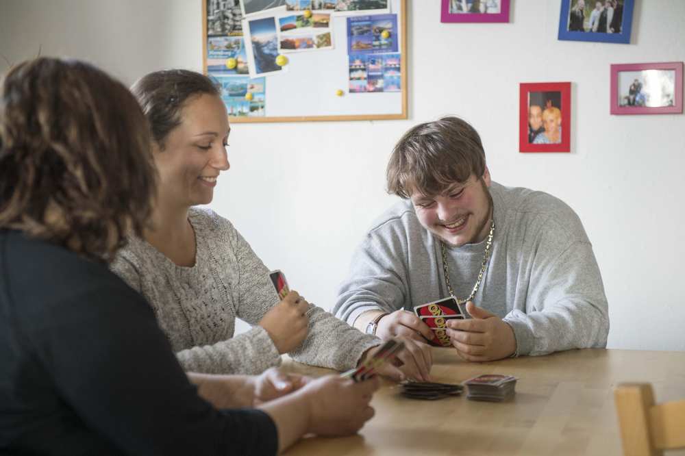 Ein Mann und zwei Frauen, die an einem Tisch sitzen und UNO spielen 