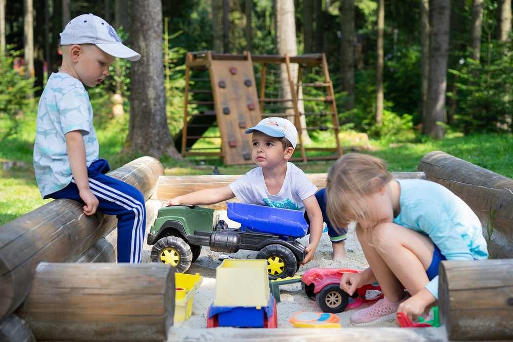 Drei Kinder spielen in einem Sandkasten