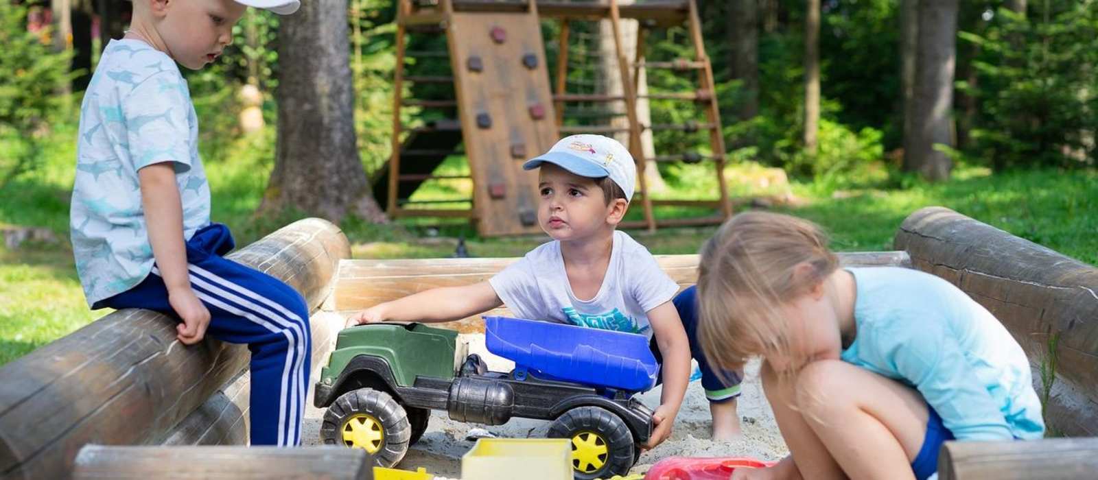 Drei Kinder spielen in einem Sandkasten