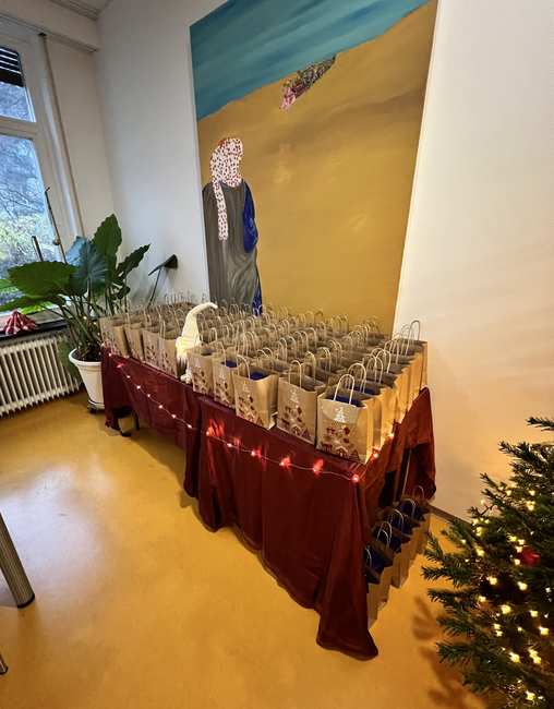 Auf einem weihnachtlich geschmückten Geschenketisch stehen viele Geschenktüten für die Klienten*innen.